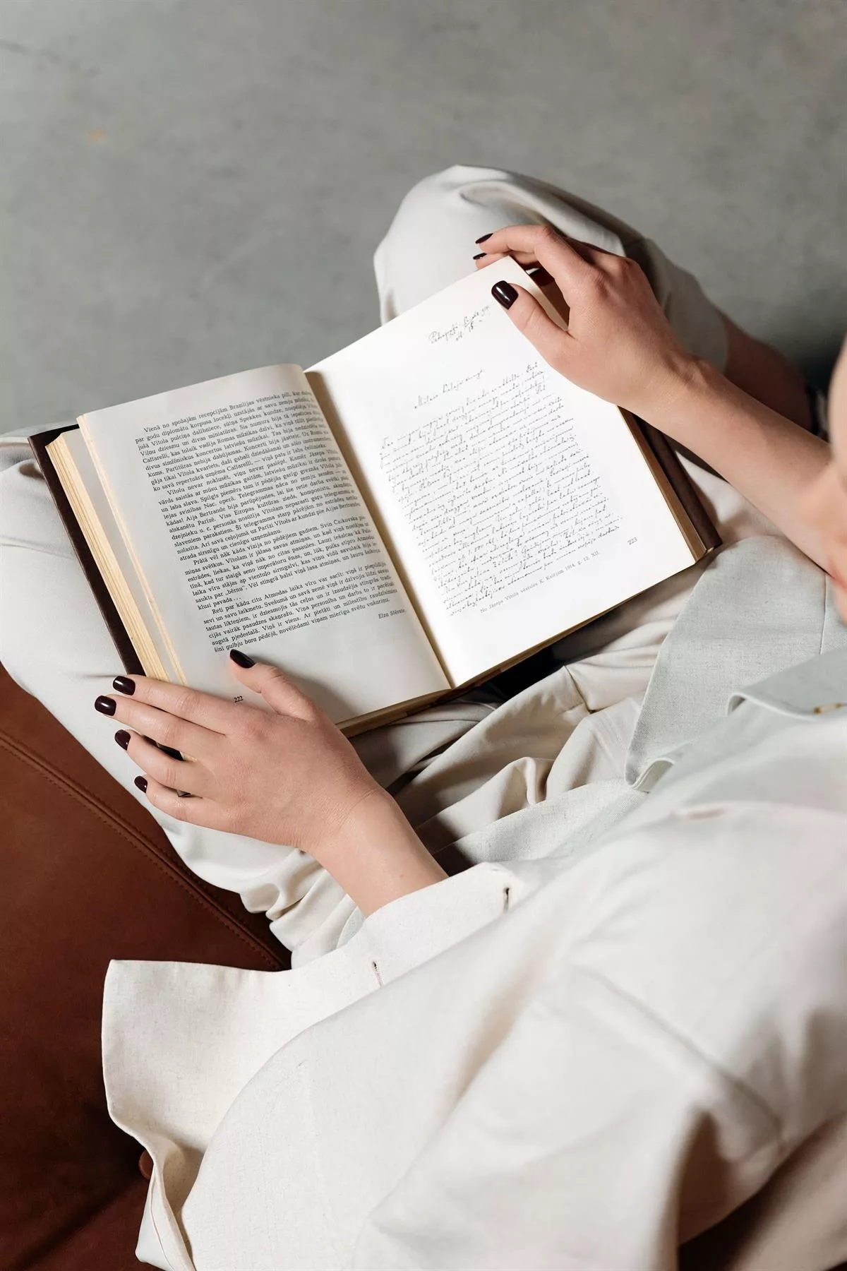 Lecture au ralenti, mains manucurées en prune foncé — vernis semi-permanent Kinetics SLOW Fall 2026, The Nail Bar